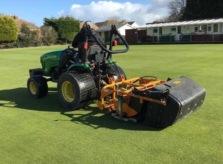 Tractor with grounds maintenance equipment on a grass playing surface
