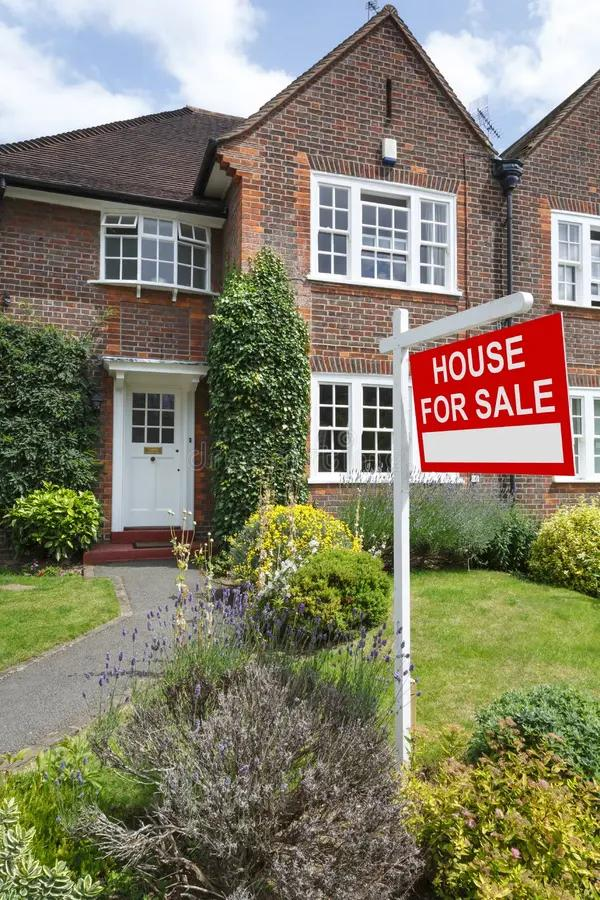 Brick house and front garden with a house for sale sign